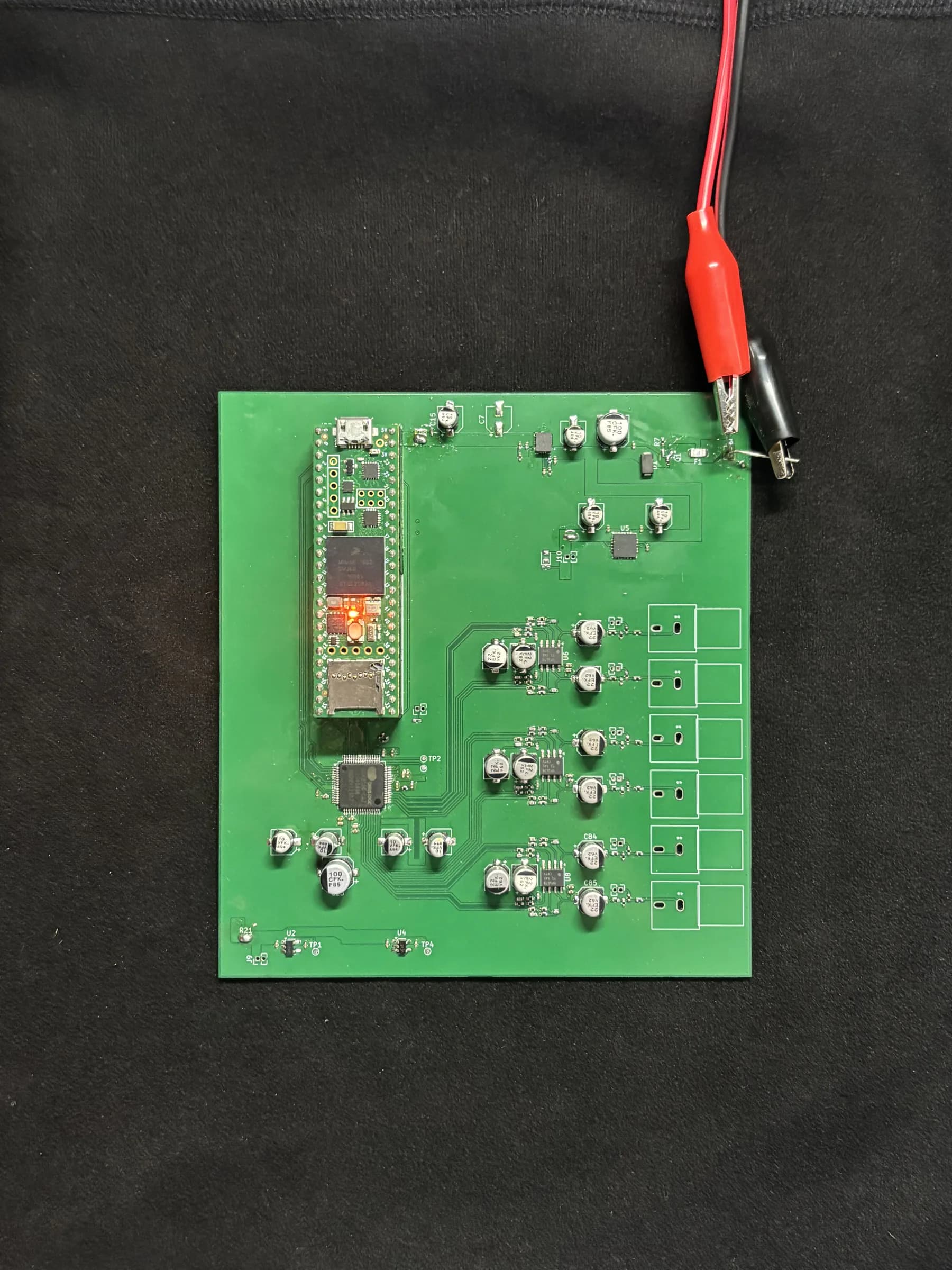 Populated DSP Revision 2 board powered on with red and black test leads.