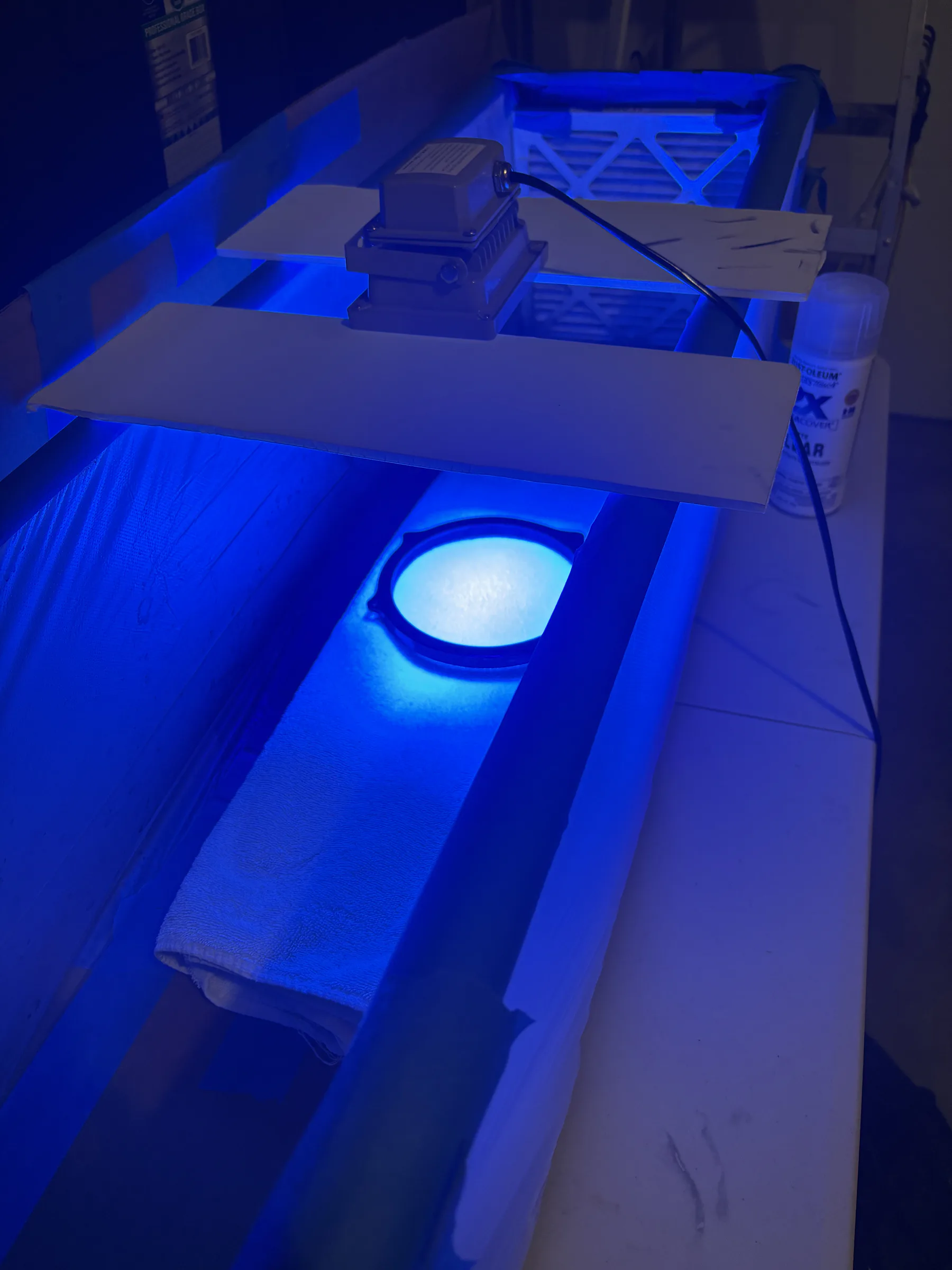 A speaker adapter curing beneath ultraviolet lights during a resin-finish experiment.